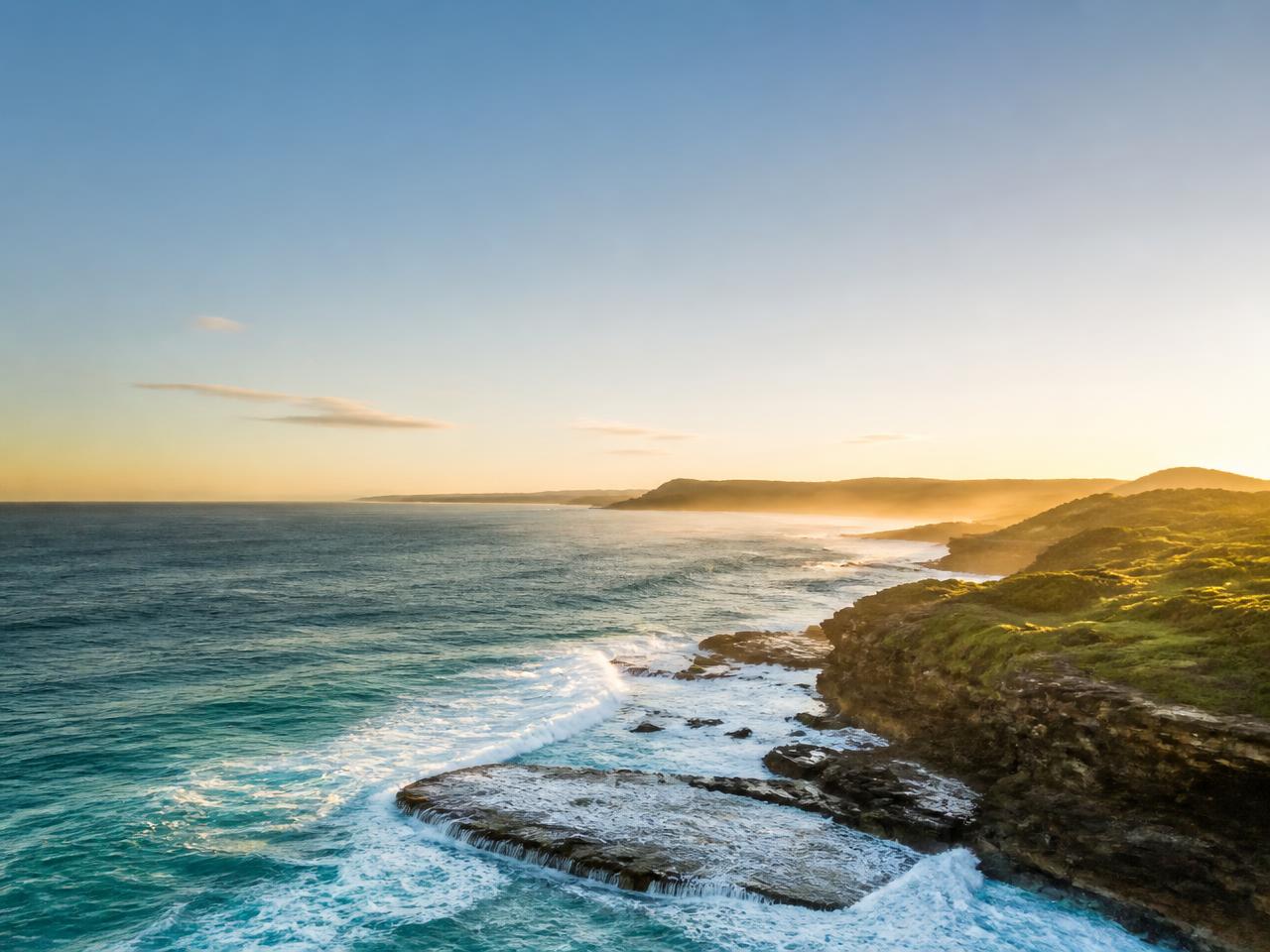 Aerial view of a rocky coastline at sunrise with copy space